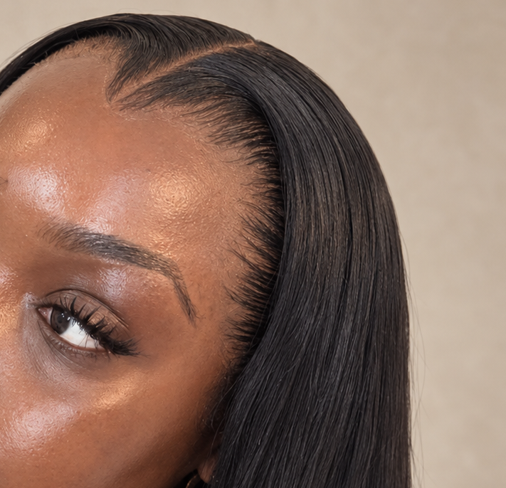 Close-up of a sleek dark hairline and side part.